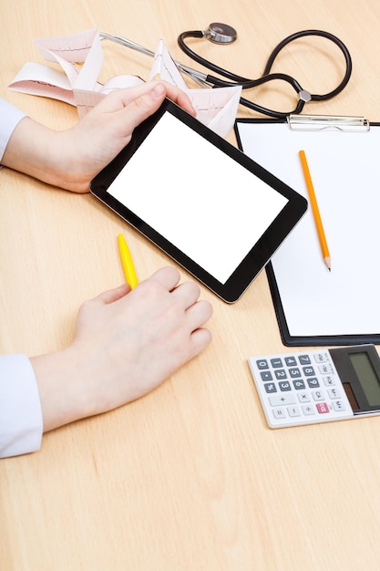 A person on the phone with their insurance company, reviewing a medical bill on a tablet, with a calculator and pen nearby.