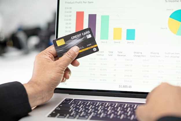 A hand holding credit cards with varying interest rates displayed on them, against a background of financial charts and graphs.