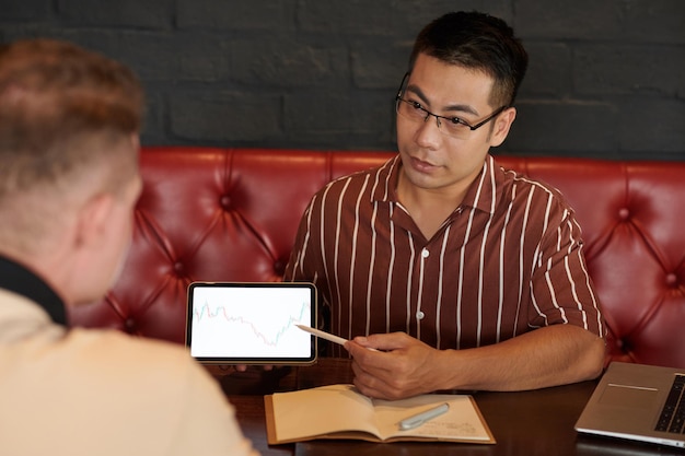 A small business owner is conducting a one-on-one interview with an employee, using a tablet to record notes. The setting is a relaxed office environment, suggesting a focus on open communication and feedback.