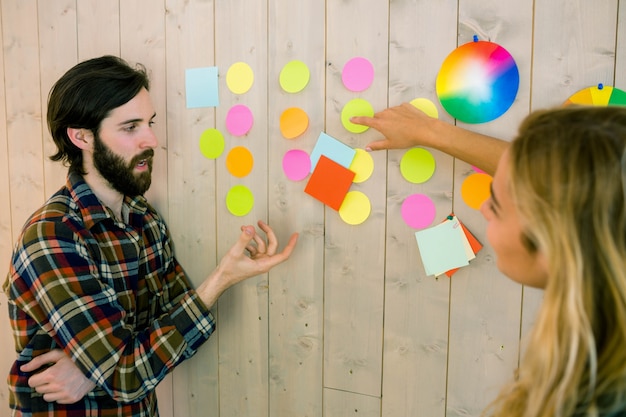 A team is brainstorming ideas in a colorful meeting room. Post-it notes cover a whiteboard, and the team members are engaged in a lively discussion, indicating a collaborative approach to problem-solving.