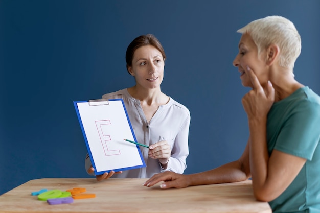 A doctor explaining the benefits of long-term disability insurance to a patient in a medical office setting. The doctor is pointing to a brochure about the insurance policy.