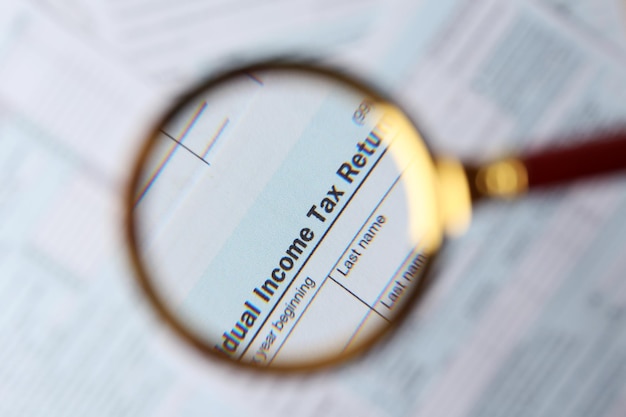 A close-up of a U.S. tax form with a magnifying glass hovering over the section related to the Child Tax Credit. The form is placed on a wooden desk with a pen and calculator nearby. The lighting is focused on the form, highlighting the importance of accuracy and attention to detail.