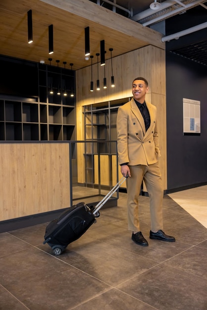 A person on a business trip, checking into a hotel with a suitcase and a laptop bag. The hotel lobby is modern and professional, indicating a business-oriented stay.