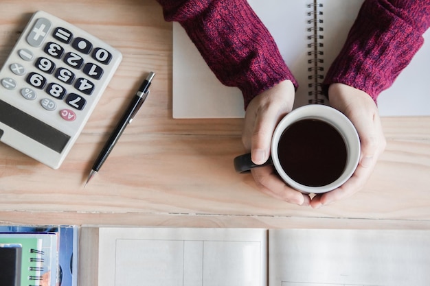 A person sitting at a desk reviewing financial documents, with a calculator and coffee cup nearby, emphasizing careful planning and financial assessment.