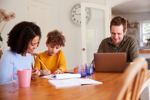 A family is sitting at a table, reviewing documents related to education expenses. They are smiling and appear to be planning for the future. A laptop is open in front of them, displaying tax forms.