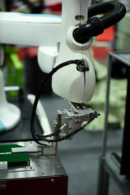 A close-up shot of a robotic arm precisely assembling a product on an assembly line, with blurred human workers in the background. The image emphasizes the precision and efficiency of automated processes.