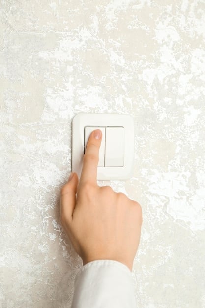 A detailed close-up of a hand turning off an unnecessary light switch in a home, symbolizing energy conservation and cost savings.