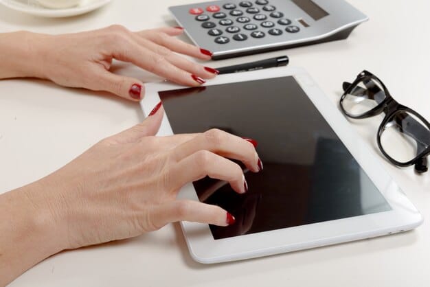 A close-up shot of a person's hands using an online HSA contribution calculator on a tablet.