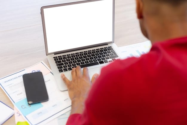 A close-up shot of an employee reviewing benefits enrollment materials on a laptop, with a cup of coffee and a notepad nearby. The focus is on the screen and the employee's thoughtful expression, highlighting the importance of informed decision-making during open enrollment.