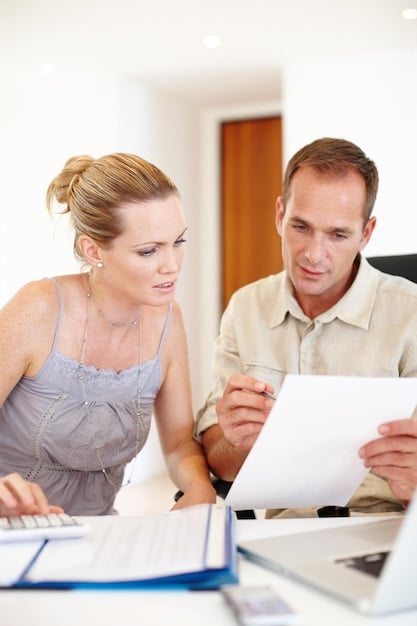 A close-up shot of a financial advisor sitting at a desk, reviewing documents with a couple. The setting implies a professional discussion regarding adoption financial assistance.